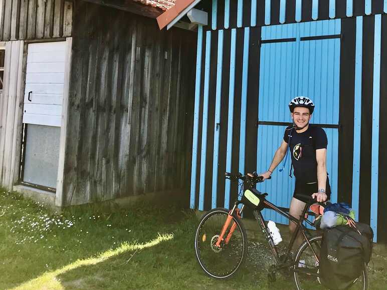 Valentin et son vélo devant une cabane colorée du port de Gujan